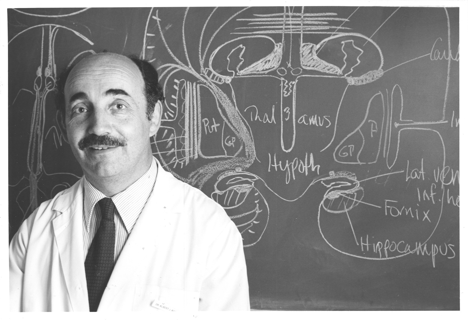 albert aguayo in front of chalk board showing a diagram of the anatomy of the brain