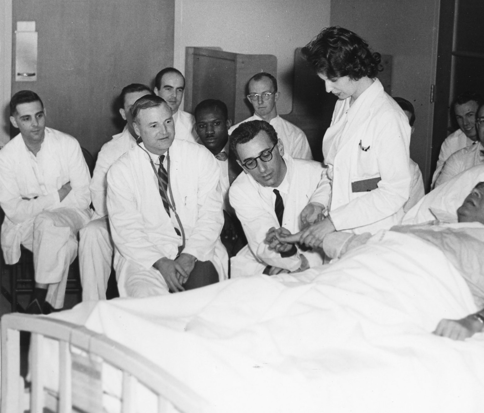 Cameron seated in centre surrounded by medical residents, patient demonstration