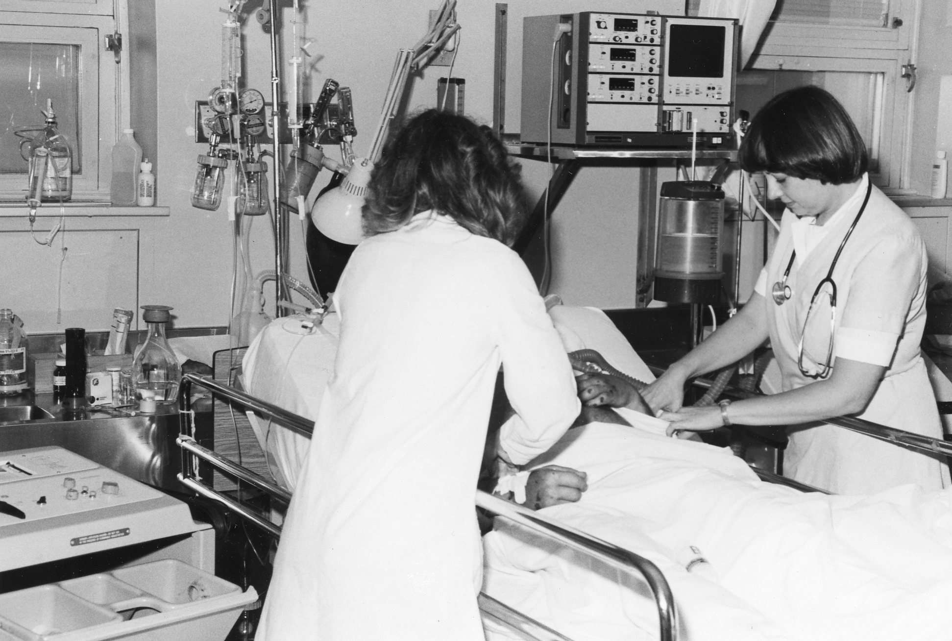 nurses attend patient in surgical icu bed with lots of machinery